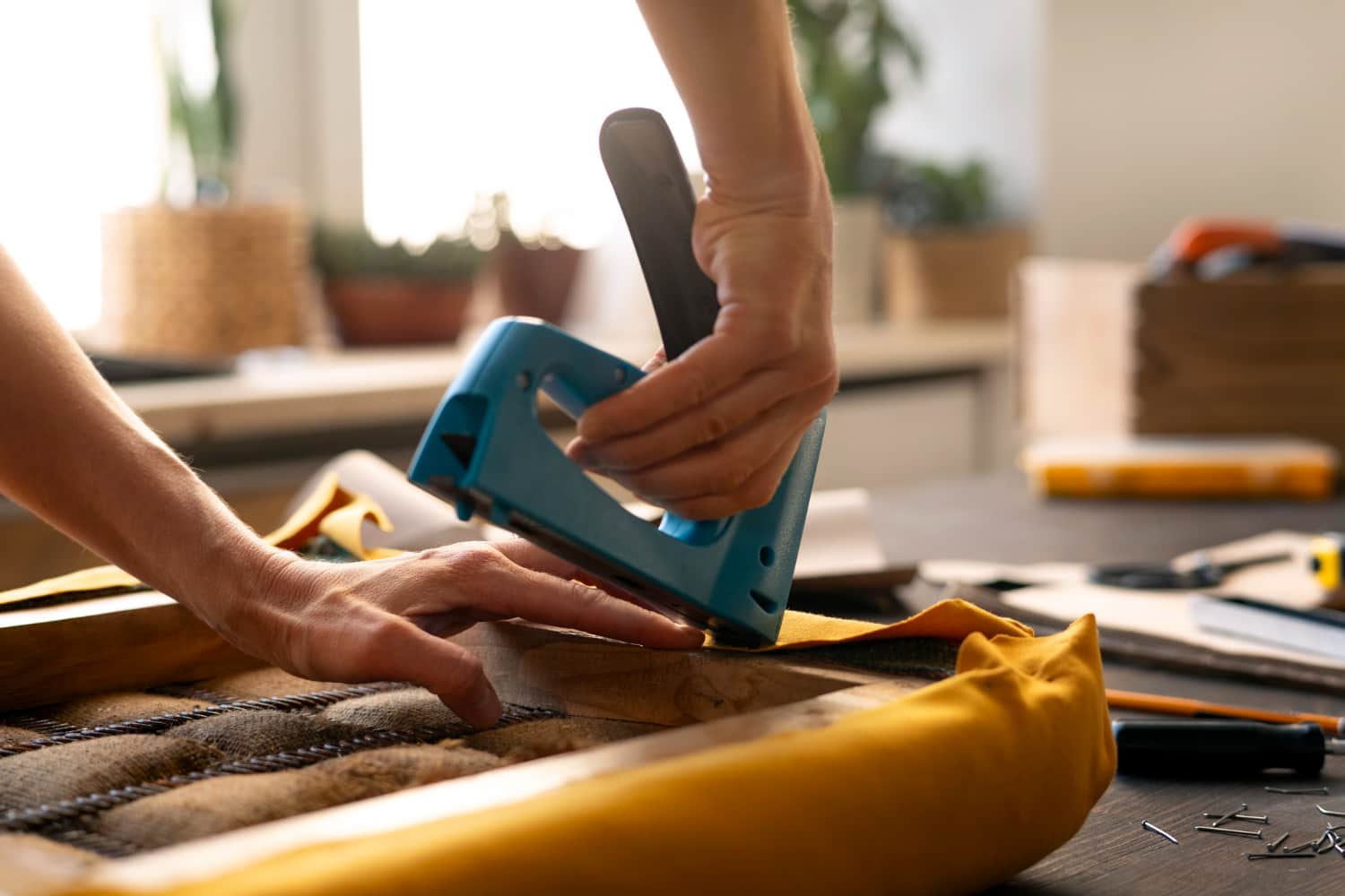 Hand using a staple gun on upholstery
