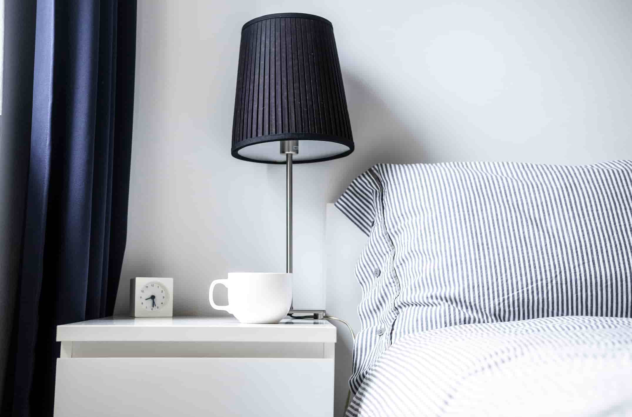 Hotel nightstand manufacturer in Turkey featuring minimalist bedside table with lamp and drawer for hotel rooms.